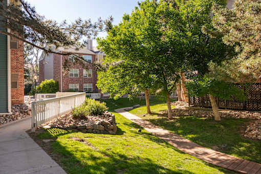 a sidewalk and trees in front of a brick building