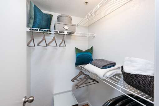 a laundry room with a chair and a shelf with towels on it