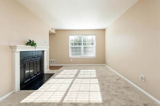 an empty living room with a fireplace and a window