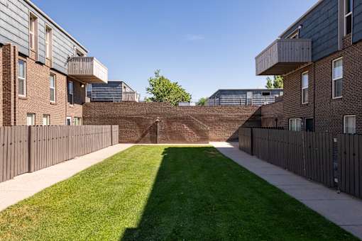 the yard of a building with a grass lawn and a brick retaining wall