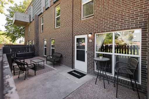 a patio with chairs and a table outside of a brick building