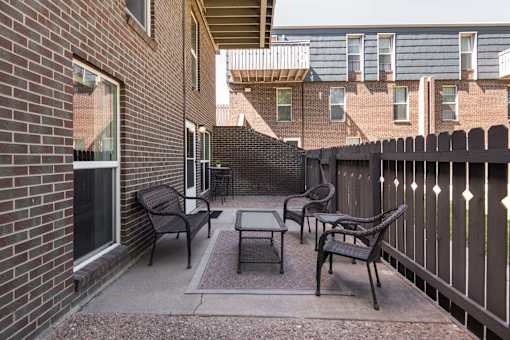 a patio with chairs and a table outside of a brick building