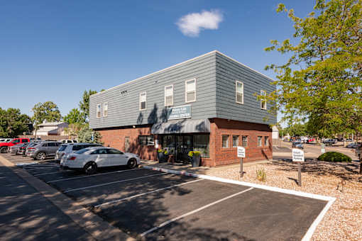 the exterior of a building with cars parked in a parking lot