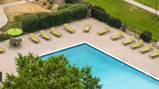 a swimming pool with yellow lounge chairs and a fence around it