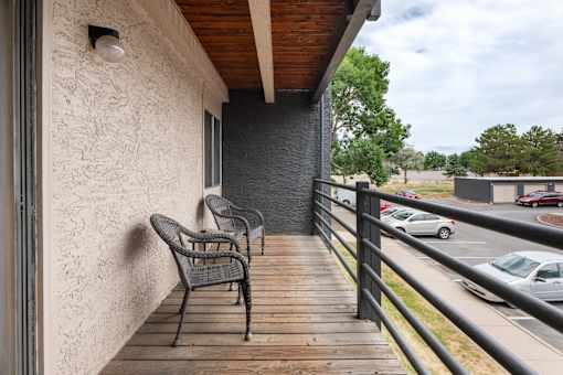 a balcony with two chairs and a building with a parking lot