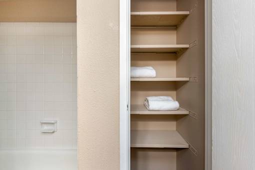 a bathroom with a closet with white towels