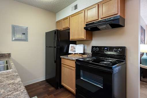 a kitchen with black appliances and wooden cabinets and a black refrigerator