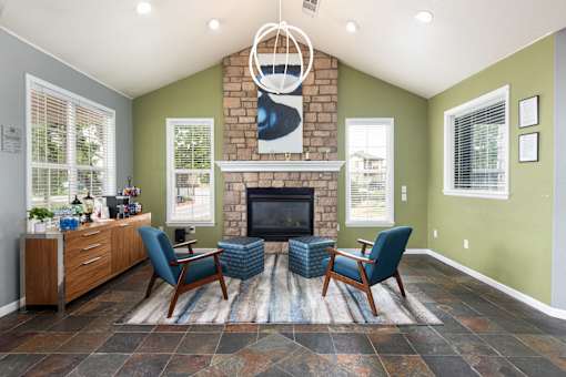 the living room has a large stone fireplace and blue chairs