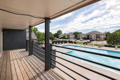 the view of a swimming pool from a balcony with wooden decking