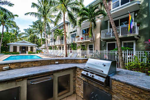 an outdoor kitchen with a grill and a swimming pool