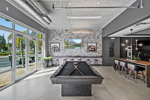 a pool table in a living room with a bar and a view of a lake