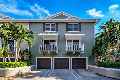 a house with two garages and two palm trees