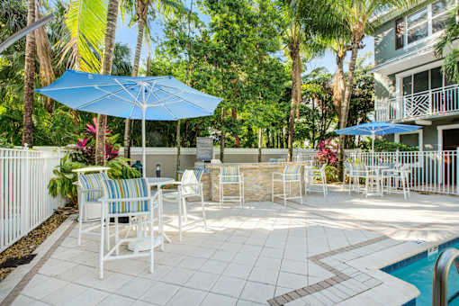 a patio with tables and umbrellas next to a pool