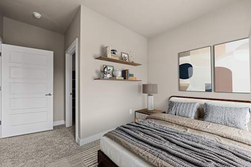 A bedroom with a bed, nightstand, lamp, and shelves.