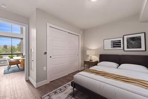 A bedroom with a large bed and a sliding door leading to a balcony.