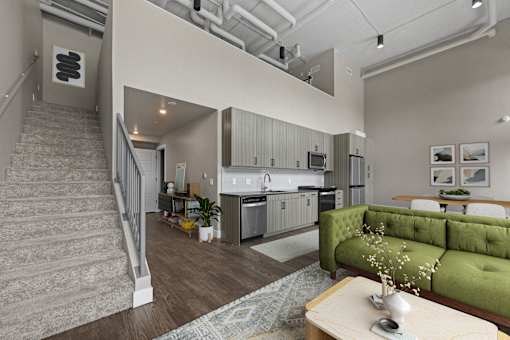 A living room with a green couch and a staircase.