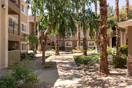 a courtyard with trees and a sidewalk in front of an apartment building