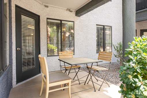 a patio with a table and chairs outside of a house
