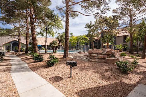 a backyard with a pool and trees and a sidewalk