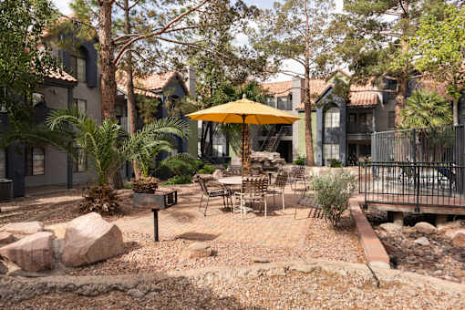 a patio with tables and an umbrella in a courtyard