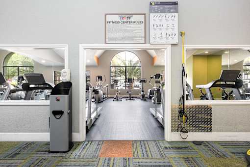 a gym with cardio equipment and a sign on the wall