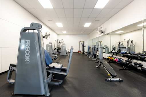 a gym with cardio equipment and weights on the floor