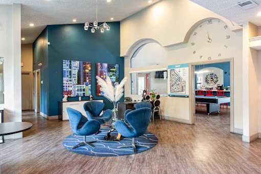 a lobby with blue chairs and a large clock on the wall