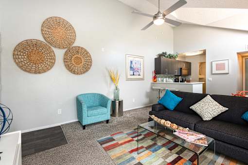 a living room with a couch and a chair and a ceiling fan