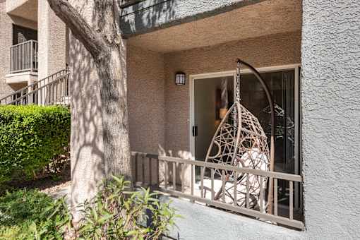 the front porch of an apartment building with a swing on it