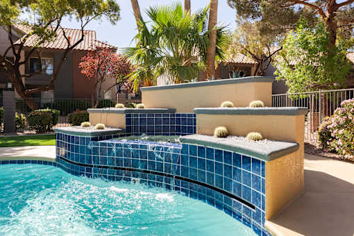 a swimming pool with a blue tiled fountain in a backyard
