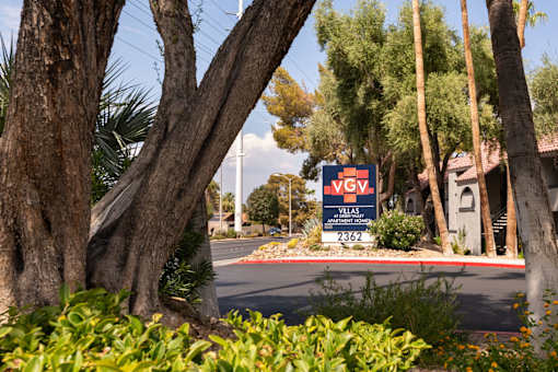 a sign for avs real estate in front of trees and bushes
