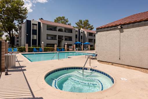 a swimming pool with a hot tub in front of an apartment building