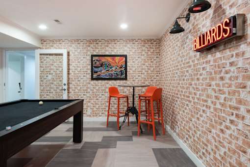 a game room with a pool table and orange chairs