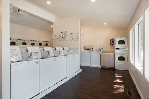 a laundry room with washers and dryers and a row of washing machines
