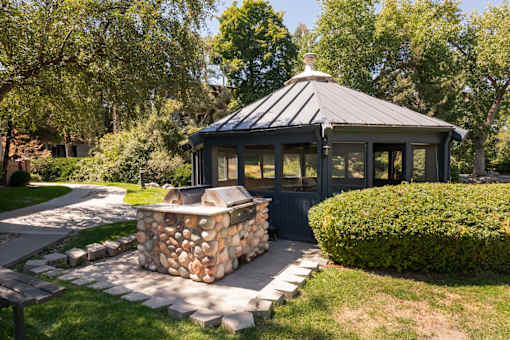 a gazebo in the backyard of a house with a stone fire pit