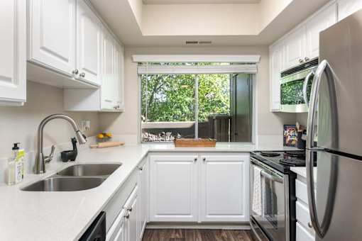 a kitchen with white cabinets and a sink and a window