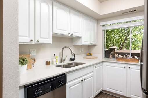a kitchen with white cabinets and a sink and a window
