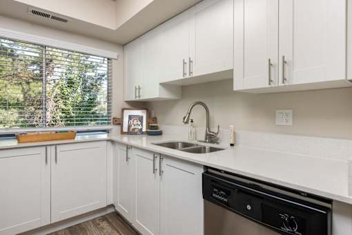 a kitchen with white cabinets and a sink and a window