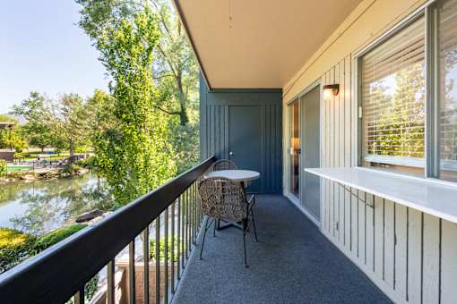 a balcony with a table and chairs and a river