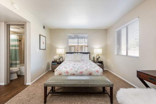 a bedroom with a bed and a stool in the middle