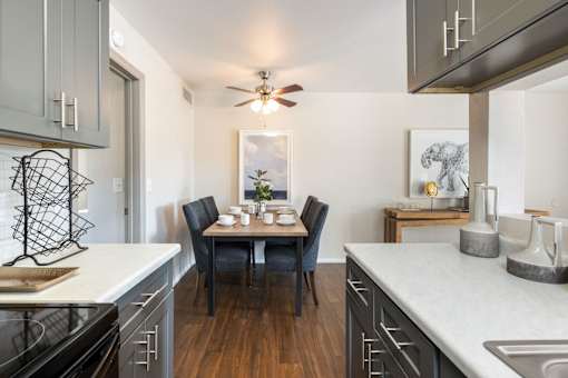 an open kitchen with a dining table and a ceiling fan