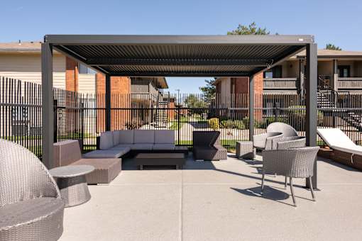 a lounge area with couches and chairs under a shade