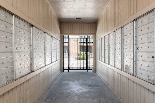 a long hallway with mailboxes and a gate