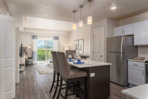 an open kitchen and dining area with a stainless steel refrigerator