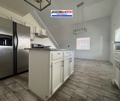 A kitchen with a refrigerator, cabinets, and a stove top oven.