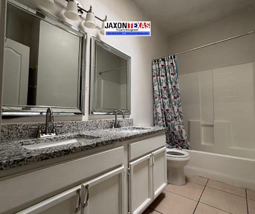 A bathroom with a sink, mirror, toilet, and shower.