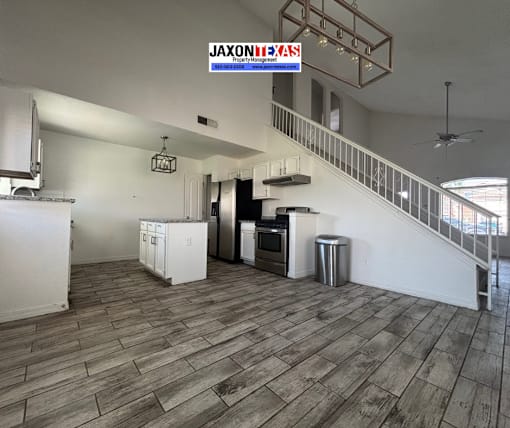 A kitchen with a wooden floor and a staircase.