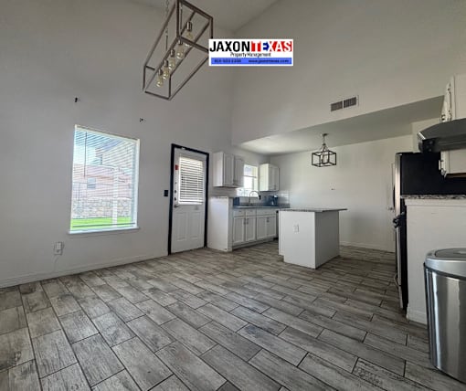 A kitchen with a wooden floor and a window with blinds.