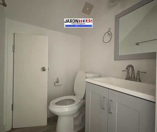 A white toilet in a bathroom with a sink and mirror.