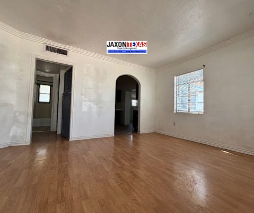 A room with wooden floors and a sign that says "Jaxontexas" on the wall.